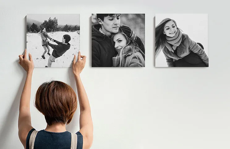 Photo canvas prints being hung on a living room wall